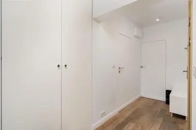 a white bathroom with white walls and a wooden floor at Bulwar Kurlandzki Downtown Apartment by BookingHost in Kraków