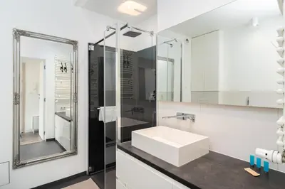 a white bathroom with a sink and a mirror at Bulwar Kurlandzki Downtown Apartment by BookingHost in Kraków