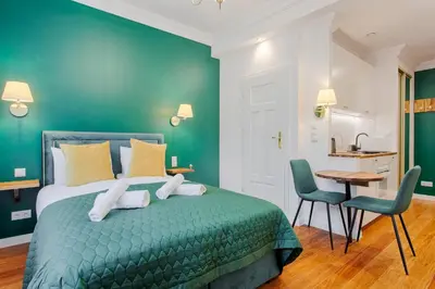 a bedroom with a green bed with two chairs and a table at Green & Gold Studio near Vistula by Tyzenhauz in Kraków