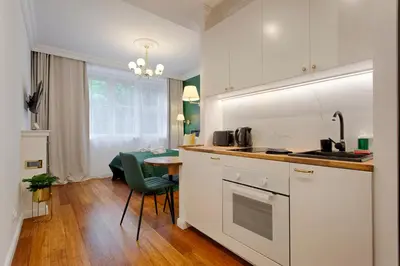 a kitchen with white cabinets and a table and a chair at Green & Gold Studio near Vistula by Tyzenhauz in Kraków