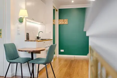 a kitchen with a table and chairs and a green wall at Green & Gold Studio near Vistula by Tyzenhauz in Kraków