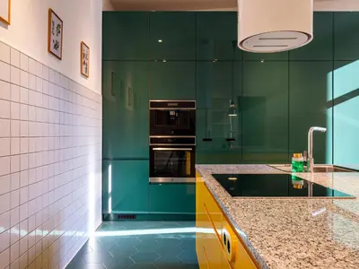 a green kitchen with a sink and a stove at Royal Vistula Luxury Apartment in Kraków