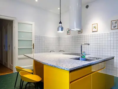 a kitchen with a sink and two yellow chairs at Royal Vistula Luxury Apartment in Kraków