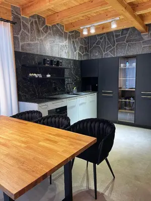a kitchen with a wooden table and black chairs at Apartament w górach SZCZEBEL in Tenczyn