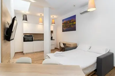 a bedroom with a white bed and a kitchen at Bosacka Downtown Apartment by BookingHost in Kraków
