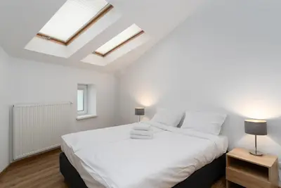 a white bedroom with a large bed and two lamps at Bosacka Downtown Apartment by BookingHost in Kraków