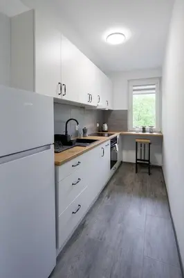a kitchen with white cabinets and a wooden floor at Spacious oasis in the center in Kraków