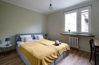 a bedroom with a bed with a yellow blanket on it at Spacious oasis in the center in Kraków