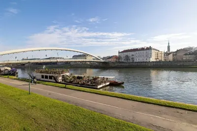 a boat traveling down a river under a bridge at Atmospheric Apartment Close to the Vistula Boulevards by Noclegi Renters in Kraków