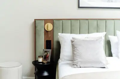 a bedroom with a white bed with a green headboard at The Garden Collection in Kraków