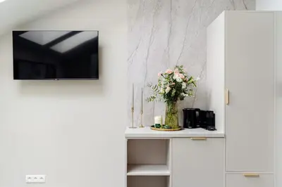 a white cabinet with a vase of flowers on a table at The Garden Collection in Kraków