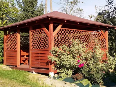a wooden gazebo in a garden with a bush at Agroturystyka Śliwkowy Sad in Biesiadki
