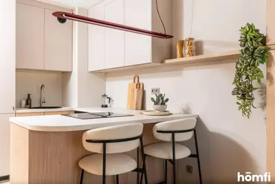 a kitchen with white cabinets and a counter with stools at Winewood Apartment - homfi Collection in Kraków
