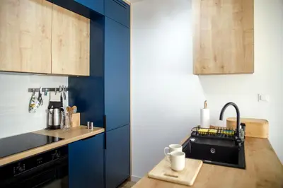 a kitchen with blue cabinets and a black sink at Krzemień Apartment in Oświęcim