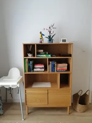 a wooden book shelf with books and a white chair at Krzemień Apartment in Oświęcim