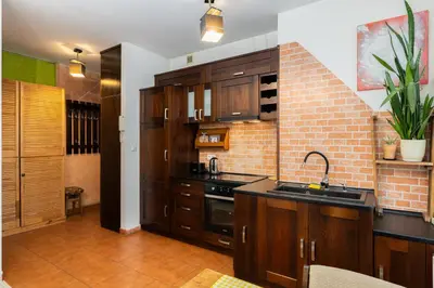 a kitchen with wooden cabinets and a sink and a stove at Bonarka Homely Studio by BookingHost in Kraków