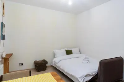 a bedroom with a bed with white sheets and a chair at Bonarka Homely Studio by BookingHost in Kraków