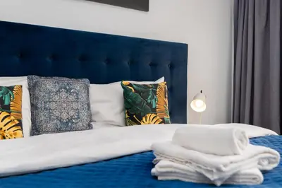 a bedroom with a bed with a blue headboard and pillows at Halicka 5 Superior Studio by BookingHost in Kraków