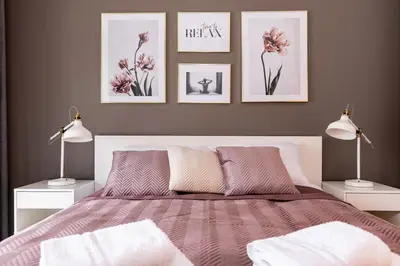 a bedroom with a bed with three pictures on the wall at Pink Boutique Apartment 60m2 & Garage in Kraków