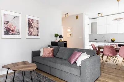a living room with a gray couch and a kitchen at Pink Boutique Apartment 60m2 & Garage in Kraków