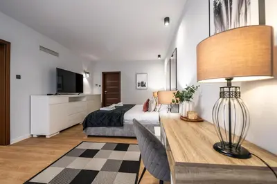 a bedroom with a bed and a table with a lamp at Carmel Apartment by Cracovia Prime in Kraków