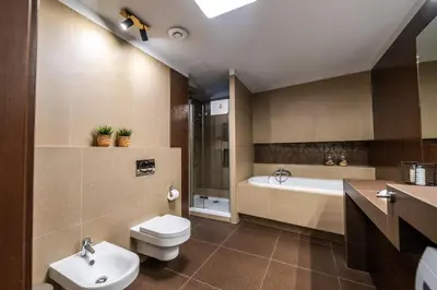 a bathroom with a toilet and a tub and a sink at Carmel Apartment by Cracovia Prime in Kraków