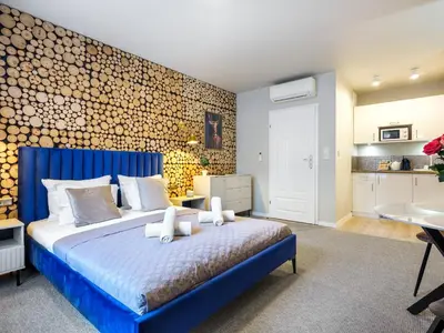 a bedroom with a blue bed and a kitchen at Boho and Forest Studios by Tyzenhauz in Kraków