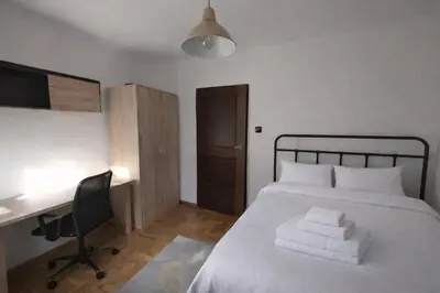 a bedroom with a bed with white sheets and a desk at Chill Apartment with Jacuzzi in Kraków
