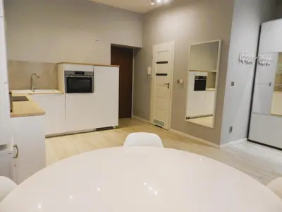 a kitchen with a white table and chairs in a room at Apartament Donnka in Kraków