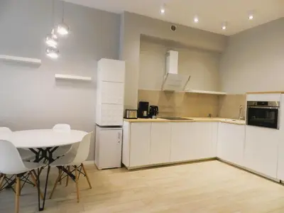 a kitchen with white cabinets and a table and chairs at Apartament Donnka in Kraków
