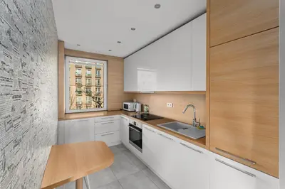 a kitchen with white cabinets and a table and a window at Nowa Huta Charming Apartment by BookingHost in Kraków