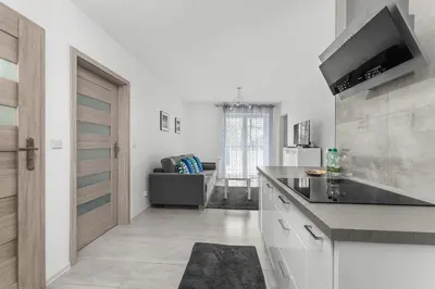 a kitchen with a counter and a living room at Bronowice Modern Apartment by BookingHost in Kraków