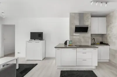 a kitchen with white cabinets and a flat screen tv at Bronowice Modern Apartment by BookingHost in Kraków