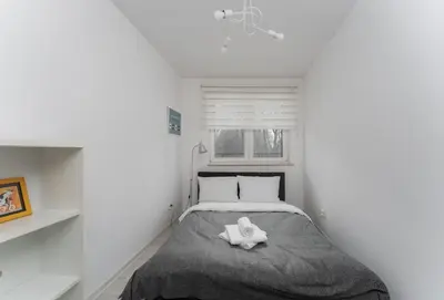 a small bedroom with a bed and a window at Bronowice Modern Apartment by BookingHost in Kraków