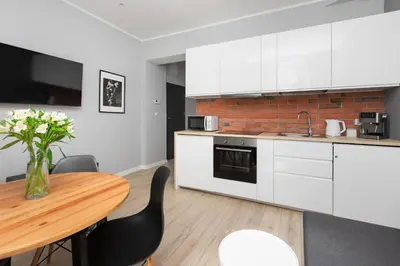 a kitchen with white cabinets and a wooden table at Native Apartments Starowiślna 33A in Kraków