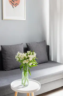 a vase of flowers on a table in front of a couch at Native Apartments Starowiślna 33A in Kraków