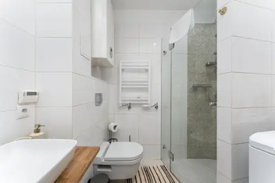 a white bathroom with a toilet and a shower at Heart of Cracow Old Town Apartment by BookingHost in Kraków
