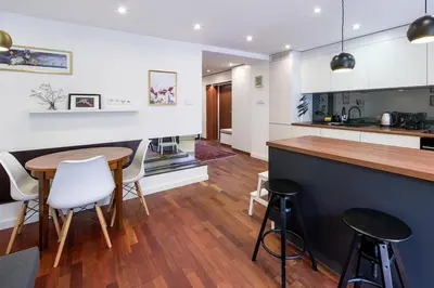 a kitchen with a wooden table and white cabinets at Unique riverside treasure in Kraków