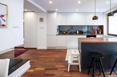 a kitchen with white cabinets and a counter with stools at Unique riverside treasure in Kraków