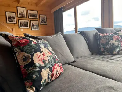 a gray couch with a floral pillow on it at Babiogórski Azyl & SPA in Zawoja