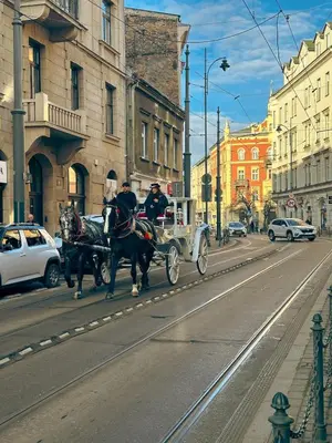 two people riding in a horse drawn carriage on a city street at Sky Studio Old Town in Kraków