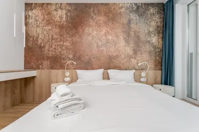 a bedroom with a white bed with a wall at Zabłocie Harmony Apartment by BookingHost in Kraków
