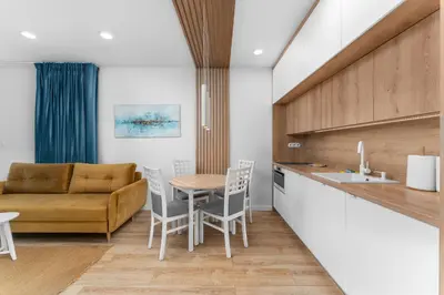 a kitchen and living room with a table and a couch at Zabłocie Harmony Apartment by BookingHost in Kraków