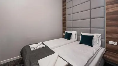 a bedroom with two beds with white sheets and green pillows at Rakowicka Residence, Sun & Snow in Kraków
