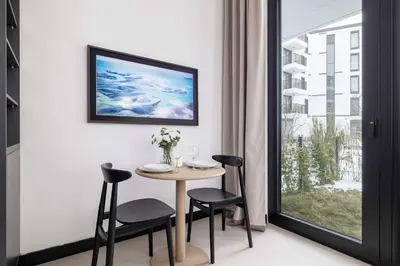 a dining room with a table and chairs and a window at Stylish Apartment with Underground Parking Located Near the TAURON Arena by Noclegi Renters in Kraków