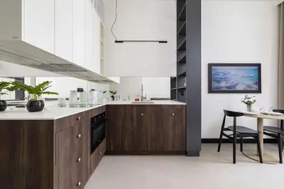 a kitchen with wooden cabinets and a table with a chair at Stylish Apartment with Underground Parking Located Near the TAURON Arena by Noclegi Renters in Kraków
