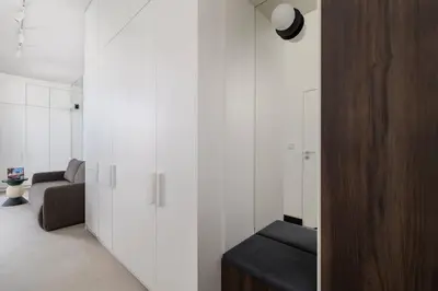 a living room with white walls and a wooden door at Stylish Apartment with Underground Parking Located Near the TAURON Arena by Noclegi Renters in Kraków
