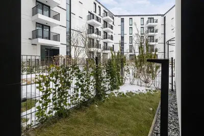 a fence with white flowers in front of a building at Stylish Apartment with Underground Parking Located Near the TAURON Arena by Noclegi Renters in Kraków