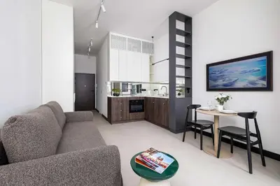 a living room with a couch and a table at Stylish Apartment with Underground Parking Located Near the TAURON Arena by Noclegi Renters in Kraków