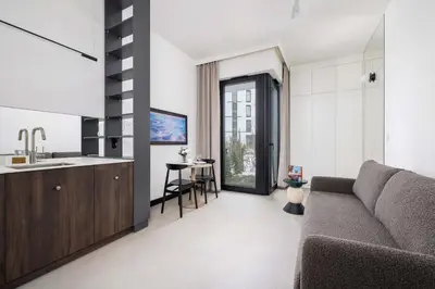 a living room with a couch and a kitchen at Stylish Apartment with Underground Parking Located Near the TAURON Arena by Noclegi Renters in Kraków